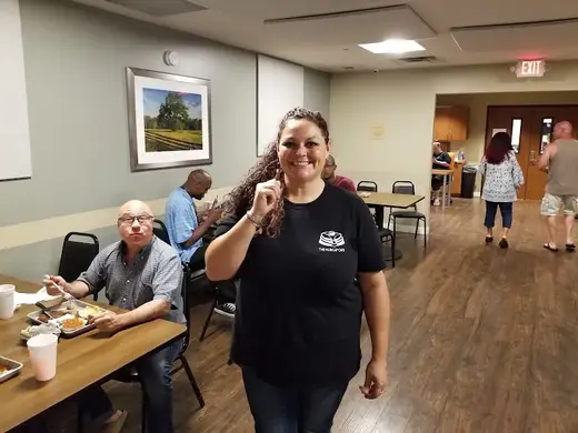 Smiling staff member in dining area at Dallas 24 Hour Club, a sober living home in Dallas.